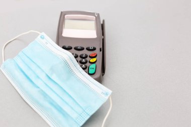 Sağlık maskeli bir savaş esiri gri bir arka planda NFC 'nin bakkaliye ödemesini bekliyor. NFC ödemesi. Covid ödemesi. Güvenli maaş..