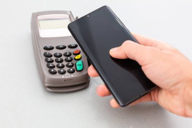 Adam faturayı ödemek için akıllı telefonda NFC teknolojisi kullanıyor.