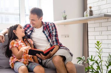 Babası evde küçük kızına İncil okuyor.