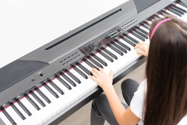 Küçük bir kız piyano çalıyor, sentezleyici.