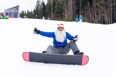 Kar maskeli ciddi bir noel baba snowboard ile ayakta duruyor. Yüksek kalite fotoğraf