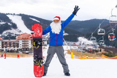 Kar maskeli ciddi bir noel baba snowboard ile ayakta duruyor. Yüksek kalite fotoğraf