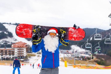 Kar maskeli ciddi bir noel baba snowboard ile ayakta duruyor. Yüksek kalite fotoğraf
