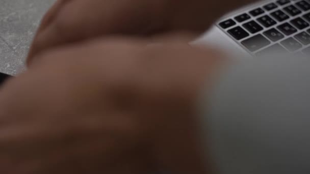 Hand aansluiten van de lader in mobiele telefoon tegen laptop computer — Stockvideo