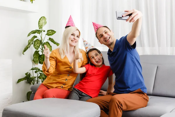 family celebrates birthday online. Mom dad kids at home mobile phone video call self-isolation. Party new technology gadgets. Coronavirus quarantined.