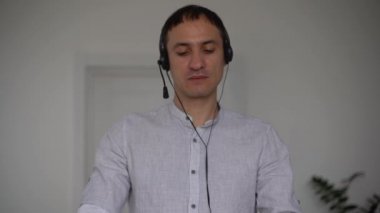 Genç erkek öğretmen kafaya mikrofon takıyor, öğrencilere uzaktan internet üzerinden problemleri anlatıyor, webcam 'e konuşuyor, ağ üzerinden bilgi paylaşıyor, karantinada uzaktan öğrenme,
