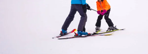 Профессиональный лыжный инструктор обучает ребенка кататься на лыжах в день на горнолыжном курорте со снегом. Активный отдых для семьи и детей. — стоковое фото