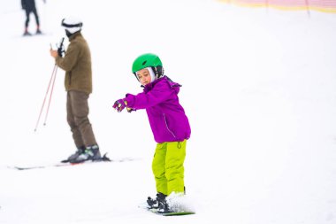 Soğuk Rüzgâr Günü 'nde Dağ Kayağı Tatil Köyü' nde Baba Küçük Kızına Snowboard öğretiyor