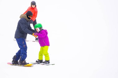 Soğuk Rüzgâr Günü 'nde Dağ Kayağı Tatil Köyü' nde Baba Küçük Kızına Snowboard öğretiyor