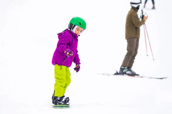 Little Cute Girl Snowboarding w ośrodku narciarskim w słoneczny zimowy dzień. — Zdjęcie stockowe