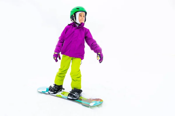 Snowboard Sports d'hiver. petite fille apprenant à faire du snowboard, portant des vêtements chauds d'hiver. Fond d'hiver. — Photo