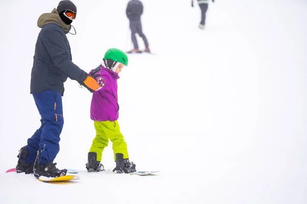 教師はスノーボードに雪の斜面で子供を教える — ストック写真