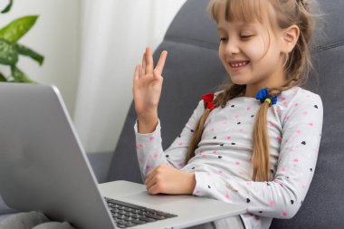 Evde bilgisayarda görüntülü konuşma yapan küçük bir kız. Metin için boşluk