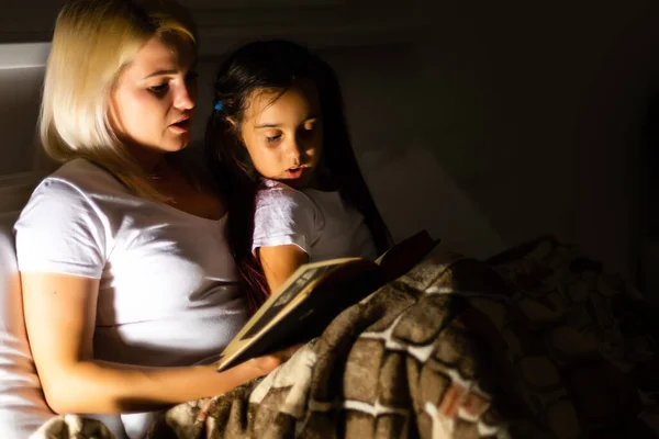 Familie bedtijd. Moeder en kind dochter lezen een boek in bed — Stockfoto