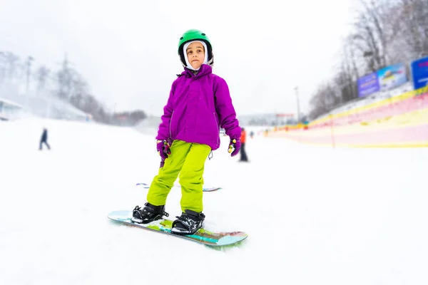 Μικρή χαριτωμένο κορίτσι Snowboarding στο χιονοδρομικό κέντρο στην ηλιόλουστη μέρα του χειμώνα. — Φωτογραφία Αρχείου