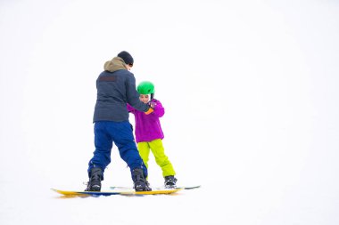 Soğuk Rüzgâr Günü 'nde Dağ Kayağı Tatil Köyü' nde Baba Küçük Kızına Snowboard öğretiyor