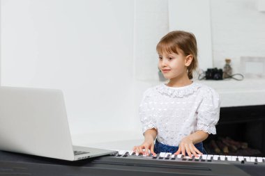 Karantina sırasında piyano öğrenen küçük bir kız. Coronavirus konsepti.