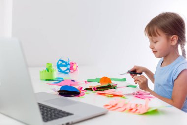 Kağıt kesen küçük bir kızın portresi Coronavirus covid-19 krizinden sonra sanat eserlerinin evde kalmasını sağlıyor. Çocuk internetten makasla kağıt kesiyor. Evde eğitim gören çocuk..