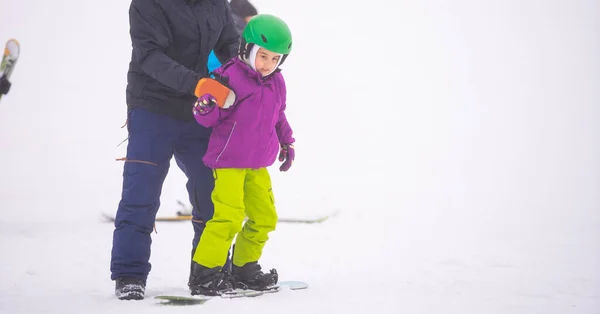 Soğuk Rüzgâr Günü 'nde Dağ Kayağı Tatil Köyü' nde Baba Küçük Kızına Snowboard öğretiyor — Stok fotoğraf