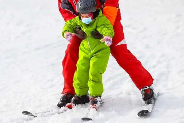 Retrato de una niña esquiadora con máscara médica durante el coronavirus COVID-19 en una montaña nevada en una estación de esquí —  Fotos de Stock