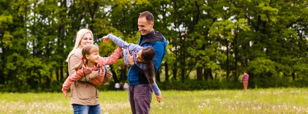 Young familiy are walking through a green field — Stock Photo, Image