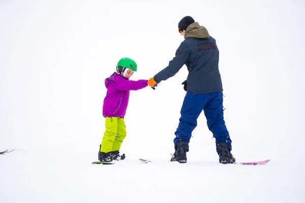 Instructeurs leren een kind op een sneeuwhelling snowboarden — Stockfoto