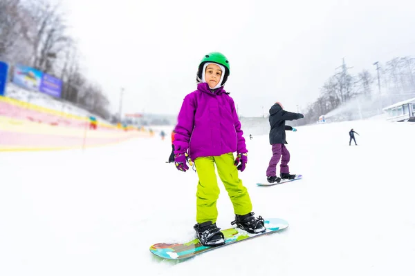 Μικρή χαριτωμένο κορίτσι Snowboarding στο χιονοδρομικό κέντρο στην ηλιόλουστη μέρα του χειμώνα. — Φωτογραφία Αρχείου