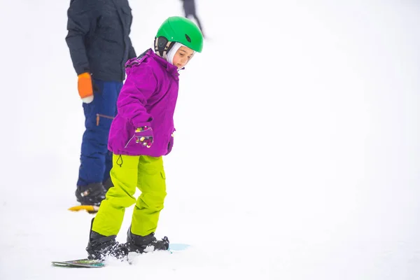 Los instructores enseñan a un niño en una pendiente de nieve a practicar snowboard —  Fotos de Stock