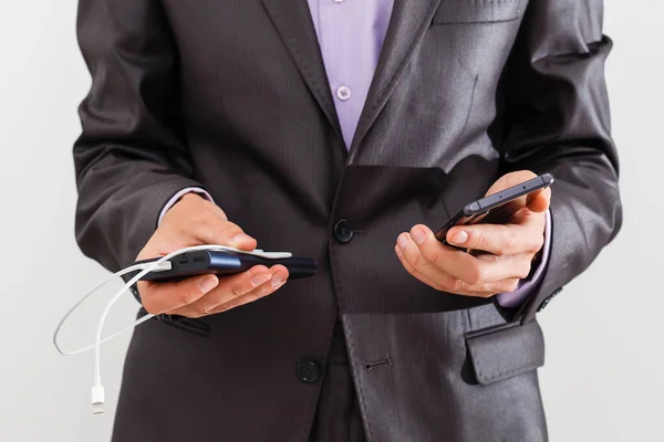 Homem detém um smartphone e uma bateria externa em um fundo branco — Fotografia de Stock