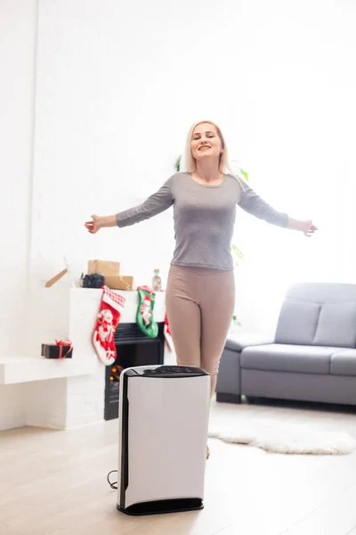 Čistič vzduchu v obývacím pokoji, žena pracující s laptopem s filtrem pro čistou místnost — Stock fotografie