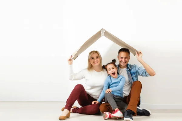 Joyeux famille assis sur le sol en bois. Père, mère et enfant s'amusent ensemble. Jour de déménagement, nouvelle maison et concept d'intérieur design — Photo