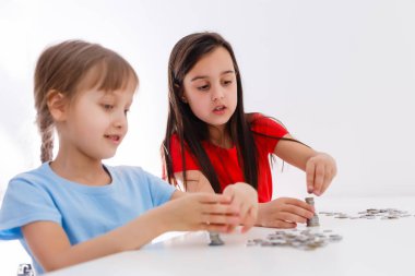 İki çocuk birlikte bozuk para sayıyor.