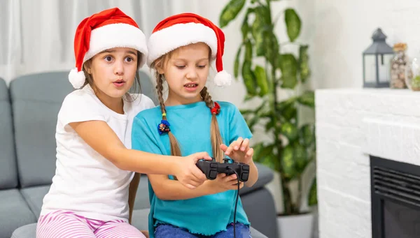 Ritratto di due belle dolci bella bella attraente divertente allegro ragazze positive in cappelli di Babbo Natale seduto su divano giocare video dispositivo battaglia — Foto Stock