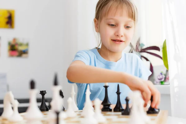 Chica moviendo un contador mientras juega al ajedrez — Foto de Stock