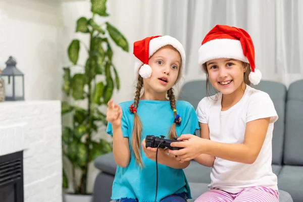 Ritratto di due belle dolci bella bella attraente divertente allegro ragazze positive in cappelli di Babbo Natale seduto su divano giocare video dispositivo battaglia — Foto Stock