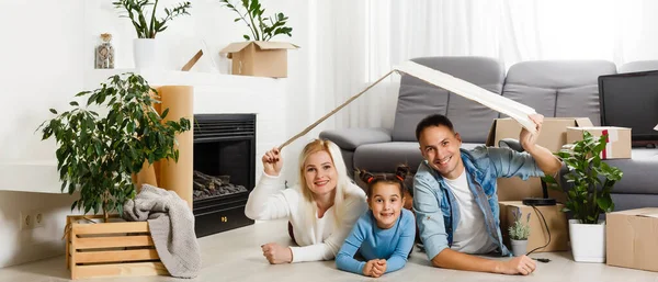 Glückliche Familie auf Holzboden sitzend. Vater, Mutter und Kind haben Spaß zusammen. Umzugstag, neues Zuhause und Design-Innenraumkonzept — Stockfoto