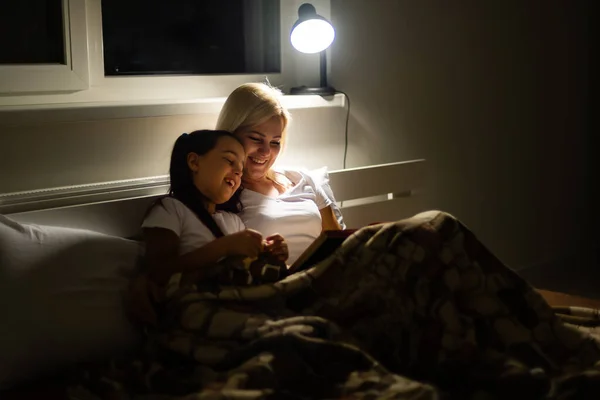 Familia feliz madre e hija leyeron un libro por la noche en casa —  Fotos de Stock