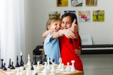 Evde satranç oynayan iki küçük kız kardeş.