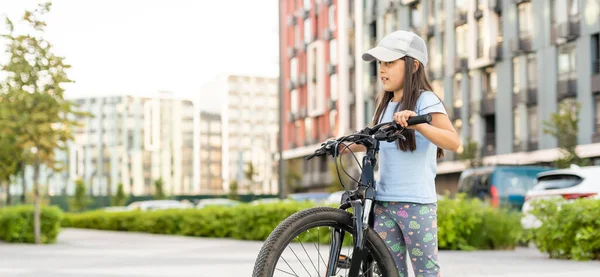 Adorable niñita montando en bicicleta en una ciudad — Foto de Stock