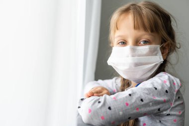 Coronavirüs salgını sırasında maske takan beyaz hasta küçük bir kız.