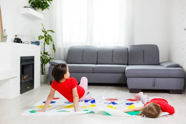 Twee gelukkige meisjes in kinderkleding spelen enthousiast op de vloer. — Stockfoto