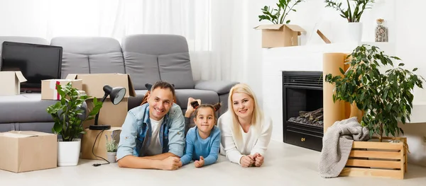 Feliz familia sentada en el suelo de madera. Padre, madre e hijo divirtiéndose juntos. Día de la casa móvil, nuevo hogar y diseño concepto de interior — Foto de Stock