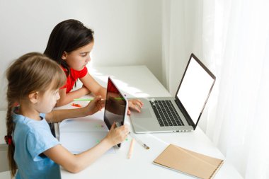 Evde öğreniyorum, evde öğreniyorum. Küçük çocuklar evde bilgisayarla online öğrenim görüyorlar. Karantina ve Sosyal Mesafe.