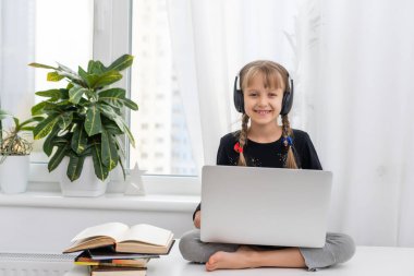 Evde bilgisayarını kullanarak internetten ders çalışan küçük bir kız.