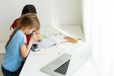 Evde öğreniyorum, evde öğreniyorum. Küçük çocuklar evde bilgisayarla online öğrenim görüyorlar. Karantina ve Sosyal Mesafe.