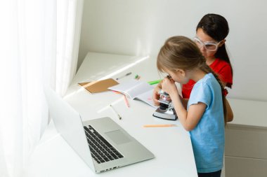 Evdeki online dersi sırasında öğrenim gören oldukça şık liseli kızlar, karantina sırasındaki sosyal mesafeler, kişisel izolasyon, online eğitim konsepti