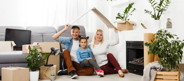 Glückliche Familie auf Holzboden sitzend. Vater, Mutter und Kind haben Spaß zusammen. Umzugstag, neues Zuhause und Design-Innenraumkonzept — Stockfoto