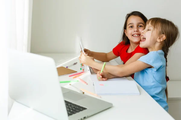 Cool escuela en línea. Los niños que estudian en línea en casa usando un ordenador portátil. Niñas alegres utilizando ordenador portátil estudiando a través del sistema de e-learning en línea. Enseñanza a distancia o remota — Foto de Stock