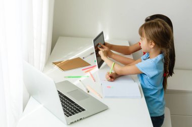 Evdeki online dersi sırasında öğrenim gören oldukça şık liseli kızlar, karantina sırasındaki sosyal mesafeler, kişisel izolasyon, online eğitim konsepti