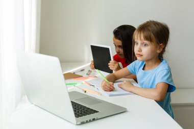 Evdeki online dersi sırasında öğrenim gören oldukça şık liseli kızlar, karantina sırasındaki sosyal mesafeler, kişisel izolasyon, online eğitim konsepti